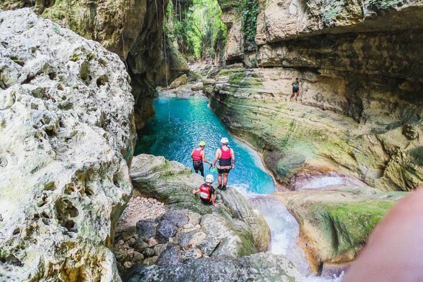 A canyon with a narrow water channel, rocky terrain, and people hiking. 5
