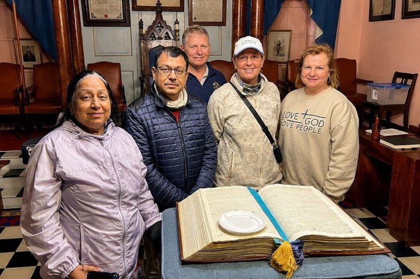 Un grupo de personas de pie en una habitación con un libro grande sobre una mesa. 1