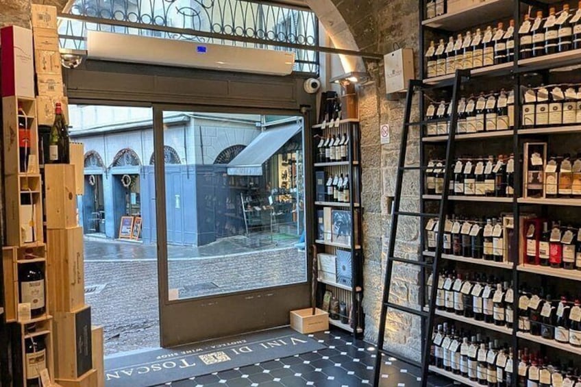 A wine shop with shelves of bottles and a view of the street outside. 3