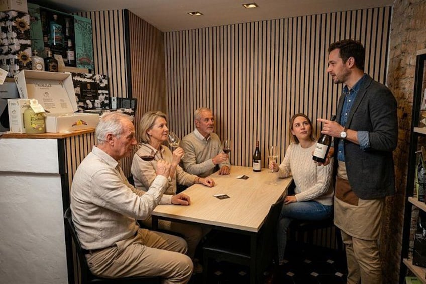 A group of people sitting around a table in a room with striped wallpaper and wooden paneling. 1