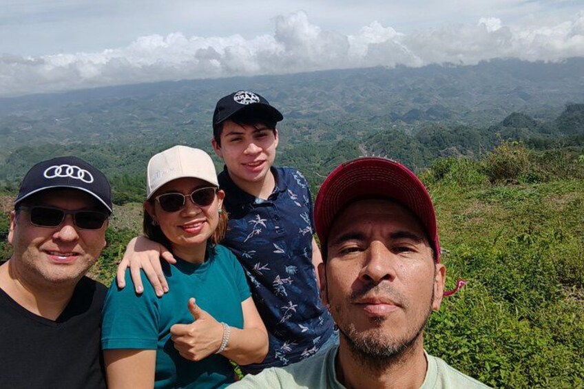 Three people standing on a hill with a view of a mountainous landscape. 5