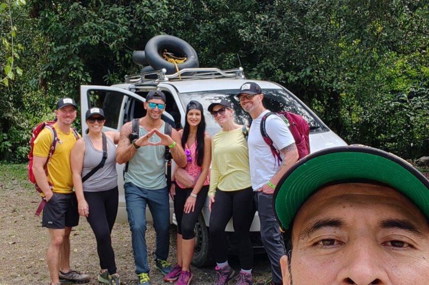 A group of people standing in front of a vehicle with a tire on top. 3
