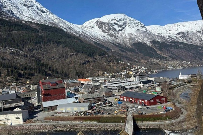 A town with buildings and a river, surrounded by snow-capped mountains. 3