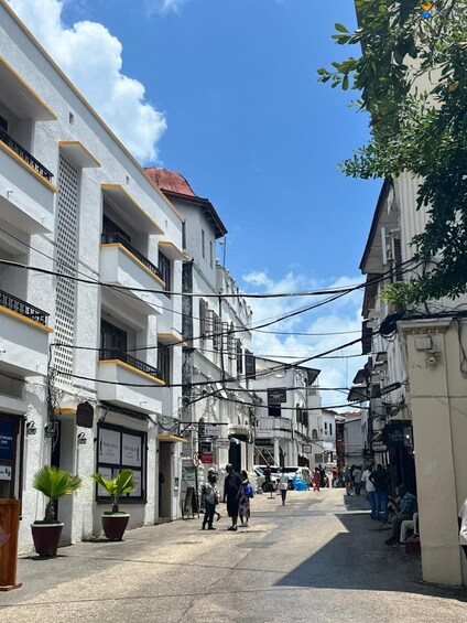 Una calle estrecha en la ciudad bordeada de edificios de varios pisos, algunos con balcones, bajo un cielo despejado. 4