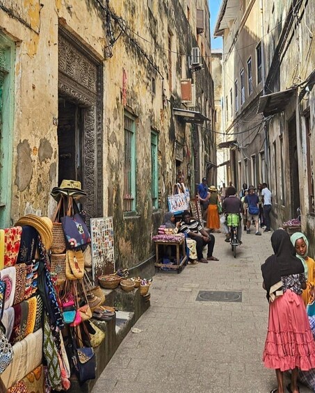 Una calle estrecha con tiendas y gente. 3