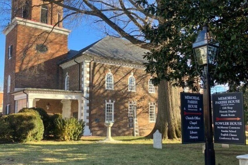 A brick building with a tower, memorial signs, and a lawn. 2