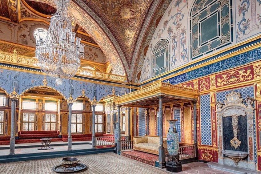 An ornate room with a large chandelier, intricate wall decorations, and a patterned floor. 2