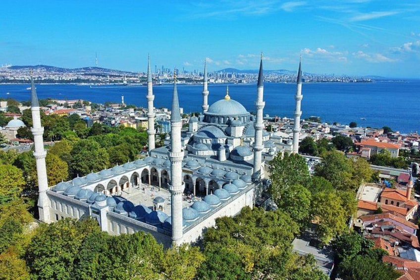 A mosque with multiple minarets and domes, surrounded by trees and a cityscape in the background. 4