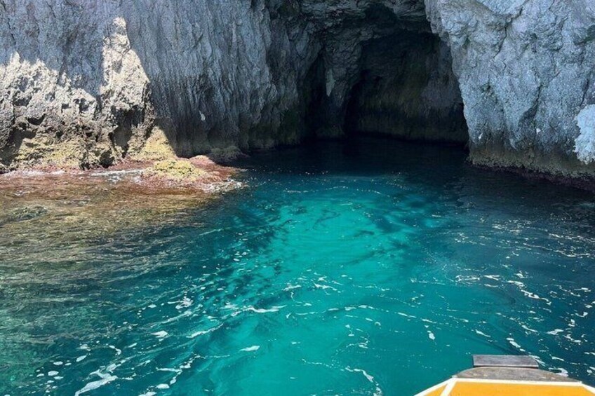Ein klares, blaues Meer mit dem Eingang zu einer felsigen Höhle. 1