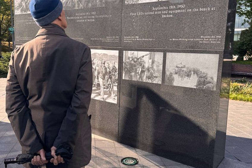 Un homme en costume et chapeau se tient devant un monument historique, des photographies et du texte étant visibles à proximité. 2