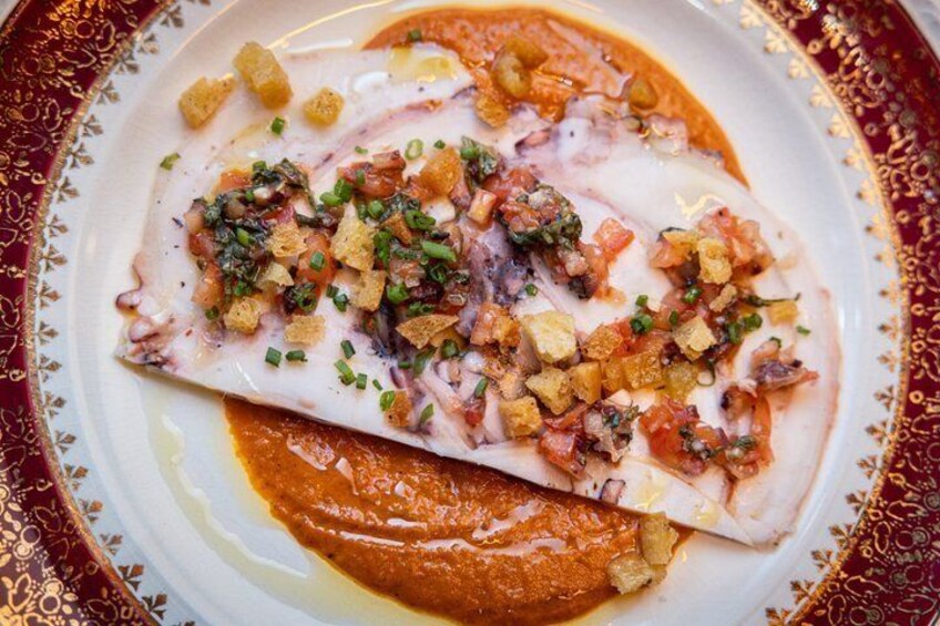 Une assiette de poisson nappé d’une sauce à base de tomates et accompagnée de croûtons. 1