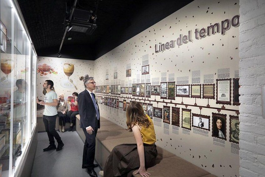 An indoor exhibition with a wall displaying framed pictures and text. 2