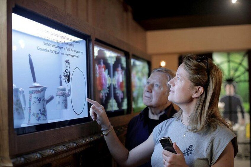 A person pointing at a digital display with text and images of teapots. 4