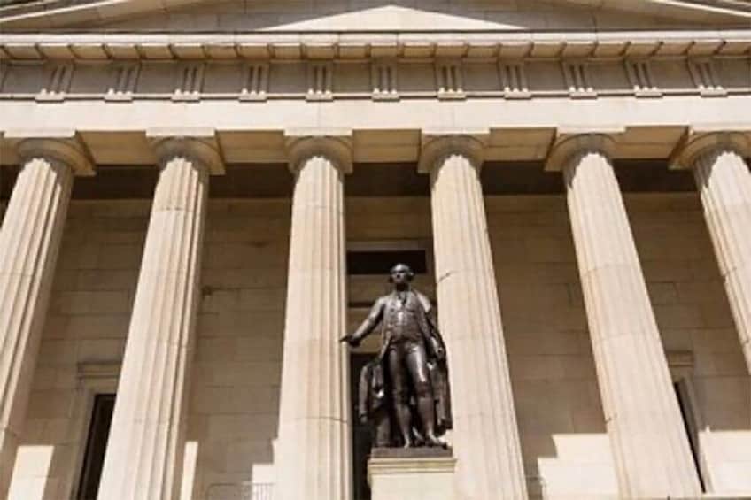 Une façade de bâtiment de style néoclassique, ornée d’une statue centrale. 4
