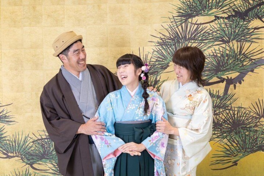 Three people in traditional attire, a pine tree illustration, and a textured wall. 4