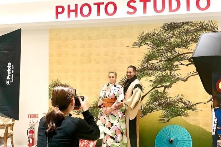 A photo studio with a backdrop of pine trees and a blue umbrella. 3