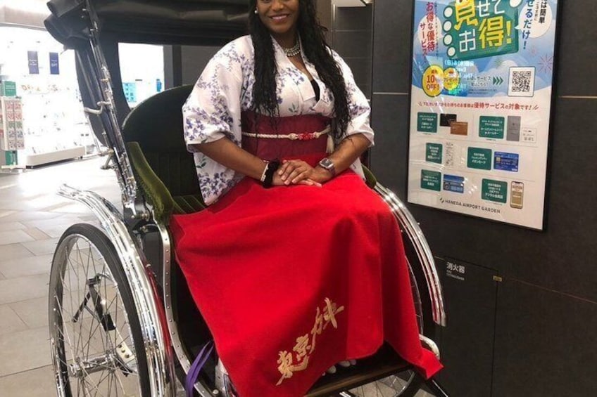 A person in a wheelchair with a red blanket, seated indoors with a poster in the background. 2