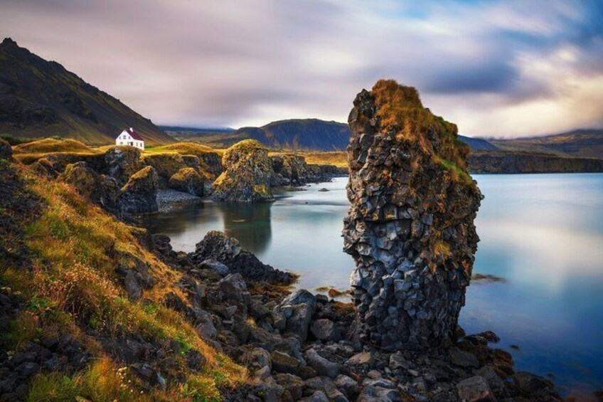 Eine Küstenlandschaft mit einer weißen Kirche, Felsformationen und einem stillen See. 4