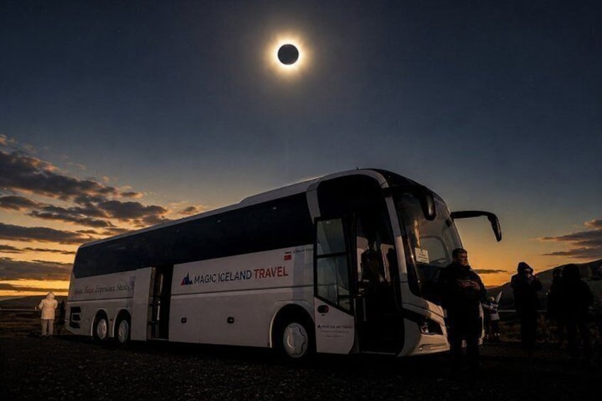 Ein Reisebus mit der Aufschrift 'Magic Iceland Travel' parkt bei Sonnenuntergang. 1