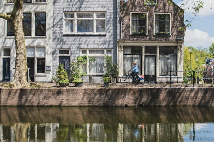 En kanal med række af huse, en cyklist og et træ. 5