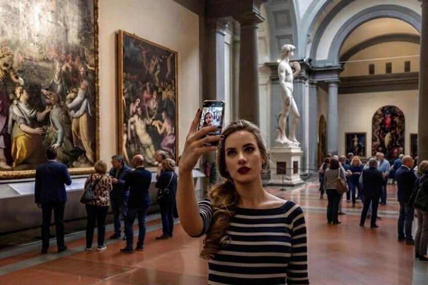 Una persona tomando una fotografía en un museo con pinturas y esculturas clásicas. 1
