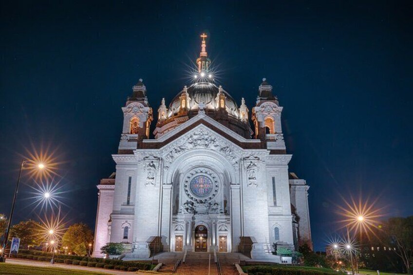 A large, ornate church with a prominent dome and cross, illuminated at night. 3