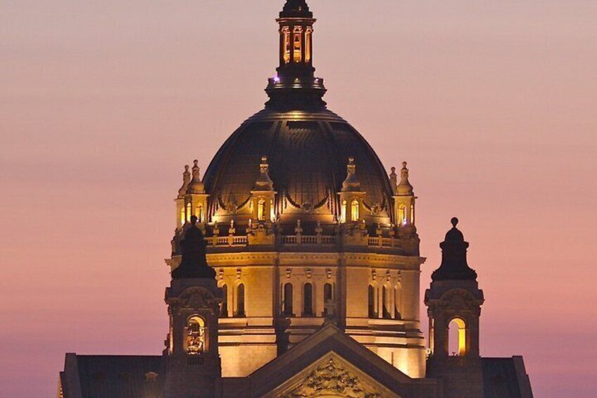 A large, illuminated dome structure with a clock tower, set against a twilight sky. 5