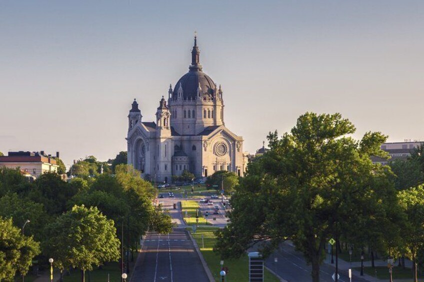 A large cathedral with a dome, surrounded by trees and a road leading to it. 1