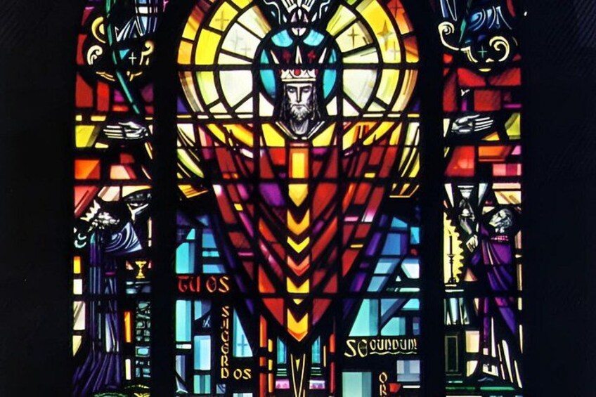 A stained glass window with a central figure, geometric patterns, and the word 'SUNDUM' at the bottom. 3