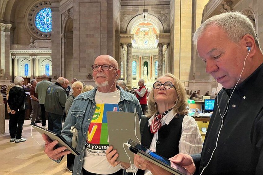 People in a church with stained glass windows and a large organ. 4