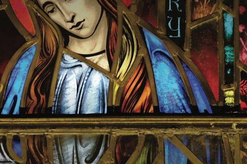 A stained glass window with a figure in blue and gold, surrounded by colorful glass pieces. 2