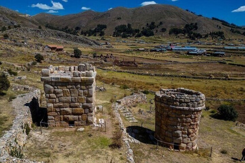 Ancient stone structures in a rural landscape with mountains in the background. 2