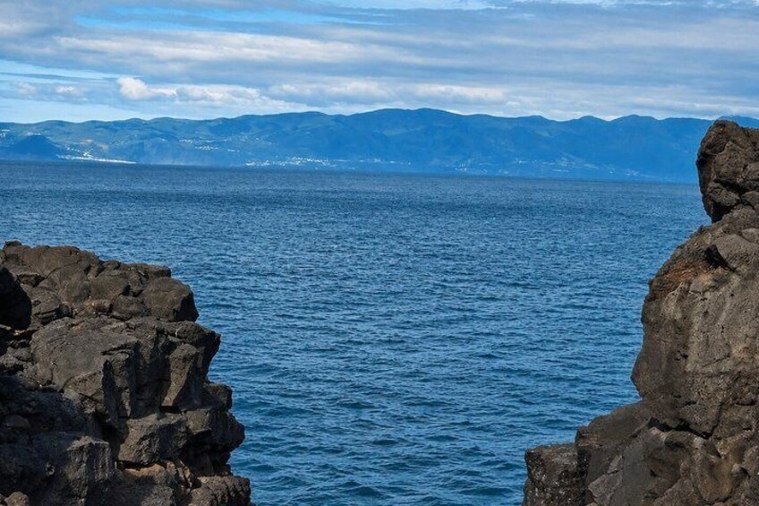 A coastal landscape with rocky cliffs and a view of distant mountains. 2