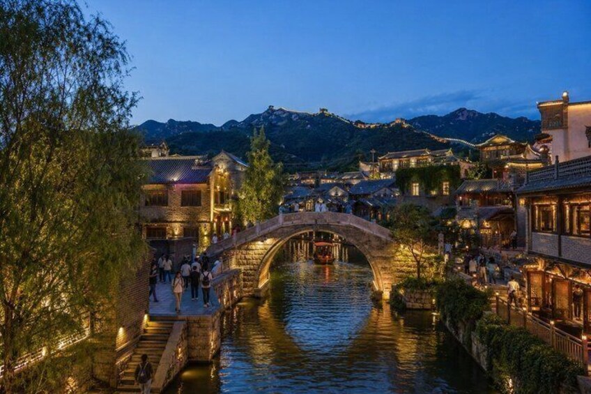 A traditional bridge over a river, surrounded by historic buildings and a mountainous backdrop. 4