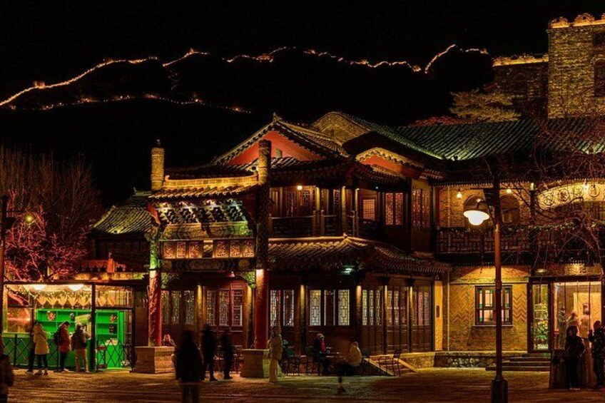A traditional building with illuminated windows and a stone tower at night. 5
