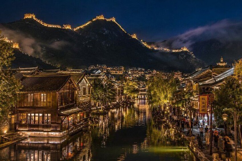 A traditional Chinese town at night with illuminated buildings and a river reflecting the lights. 3