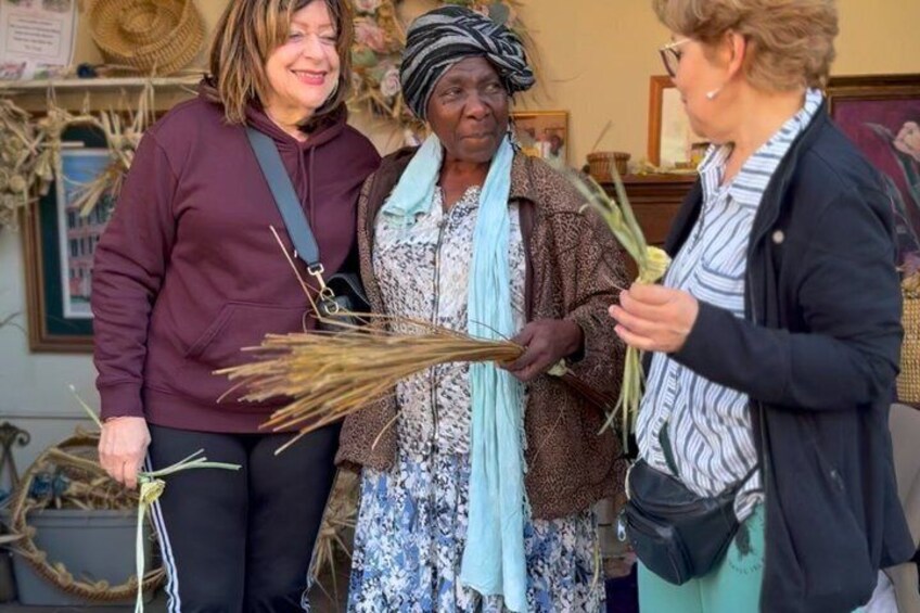 Three people holding dried plants, standing in a room with a rustic decor. 1