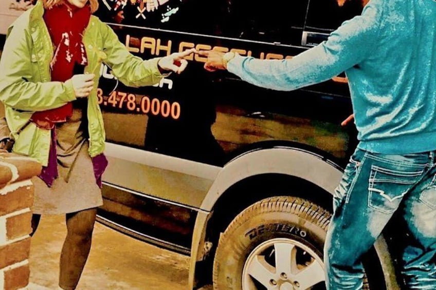 A person handing over a white object to another person in front of a vehicle with a phone number on it. 4