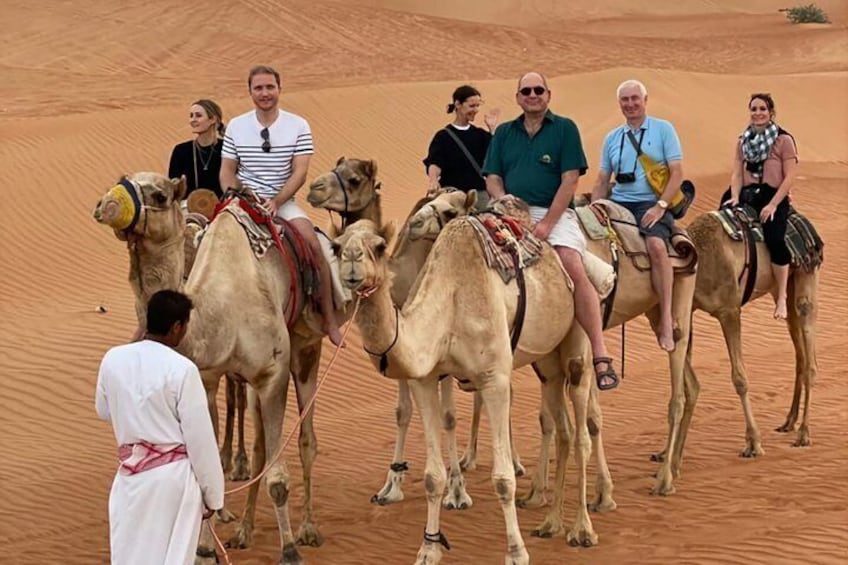 A group of people riding camels in a desert. 5