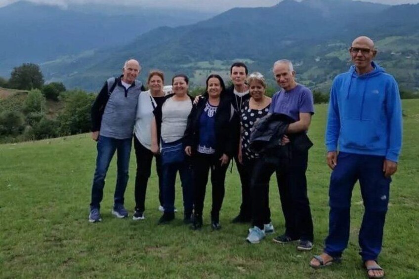 A group of people standing on a grassy hill with a mountainous landscape in the background. 5