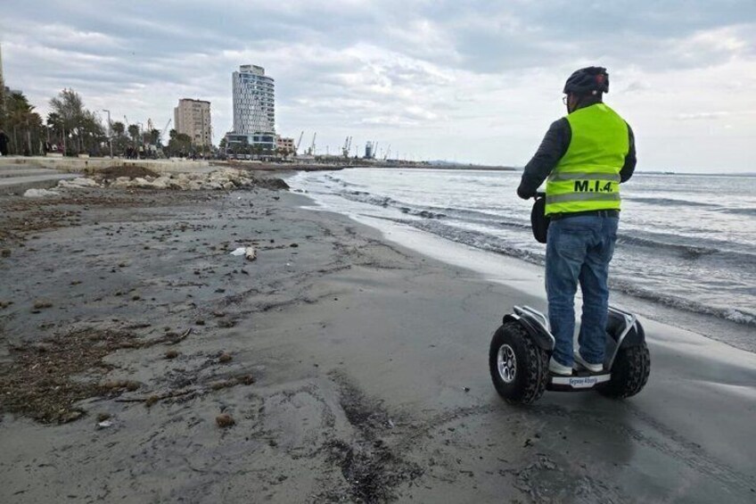 A person on a Segway near a beach with a building in the background. 2