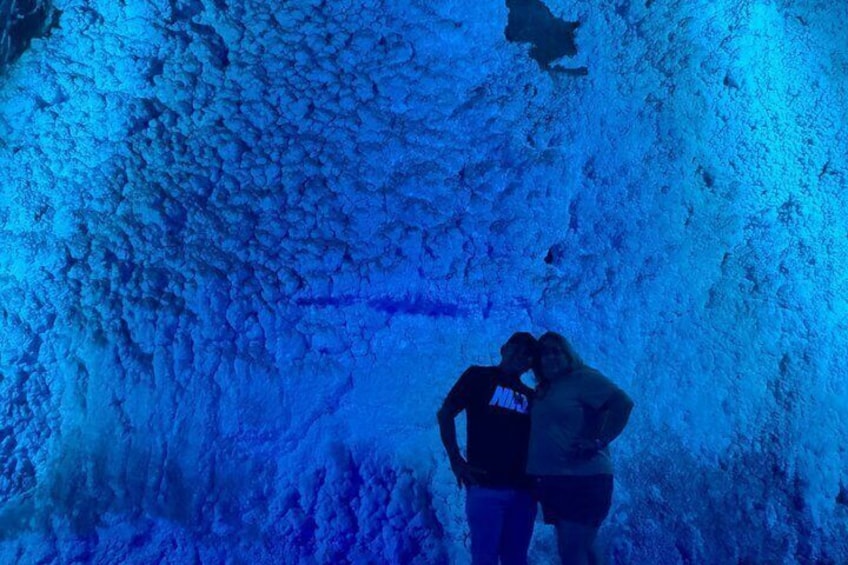 A person standing in a cave with a textured wall. 4