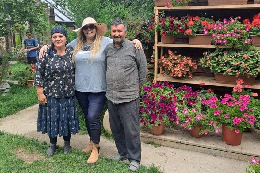 Three people standing in front of a garden with a variety of potted plants. 1