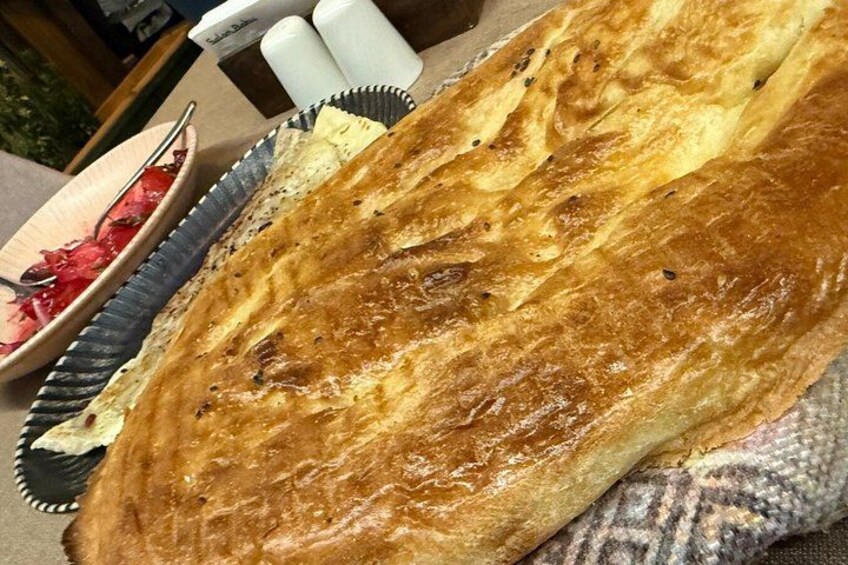 A loaf of bread with a golden-brown crust, a bowl of red fruit, and salt and pepper shakers. 2