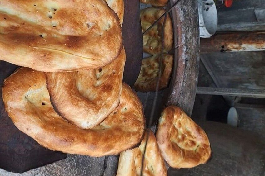 A stack of freshly baked bread with a golden-brown crust, hanging from a wooden rack. 5