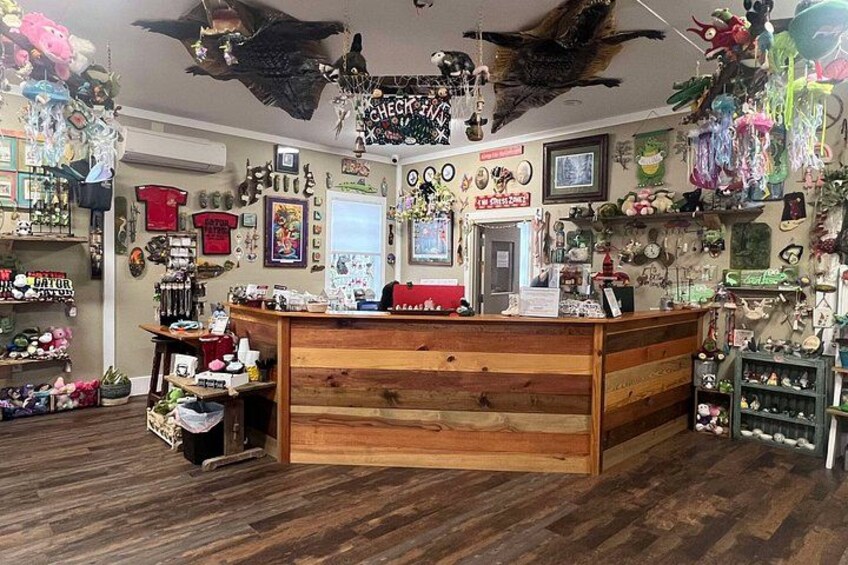 A cluttered room with a wooden counter, various stuffed animals, and numerous hanging items. 3