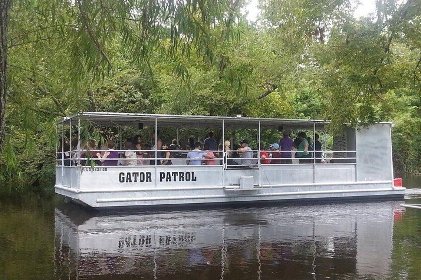 A boat named Gator Patrol on a river surrounded by greenery. 2