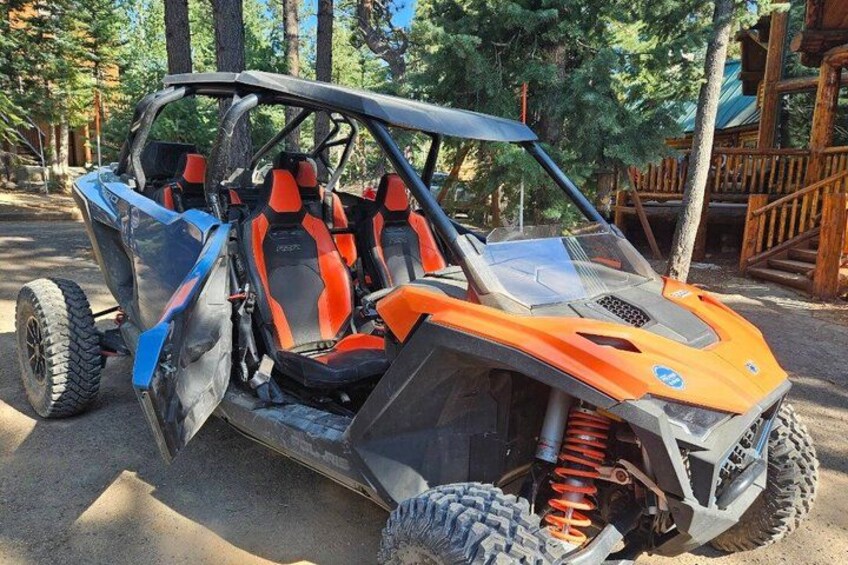 A four-wheeled off-road vehicle with a raised suspension, large tires, and a cabin with orange and black seats. 2
