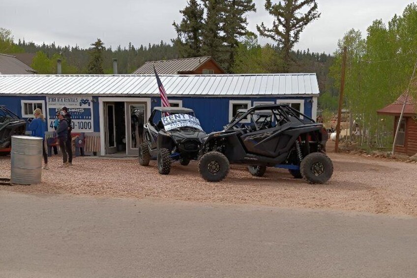 A rental ATV with a flag, a building with a sign, and a gravel driveway. 3