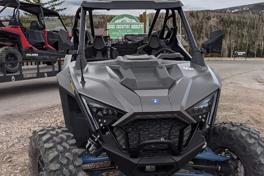 A Polaris ATV parked in a gravel area with a sign in the background. 2
